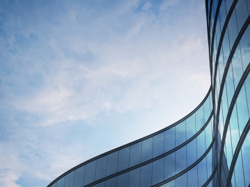 curved glass building looking up at a blue sky
